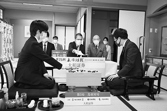 이틀거리바둑 둘째날 대국 개시 장면. 입회인 야마시로 히로시 九단(가운데)이 시바노 九단의 첫날 봉수점을 적은 기보용지를 이야마 九단(오른쪽)에게 확인케 하고 있다.